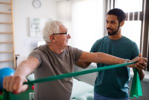 Physical therapy for seniors: A young therapist assists an elderly patient with exercises in a clinic room, focusing on improving mobility and strength