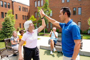 Physical therapist and older senior woman rejoicing health success with a high five.