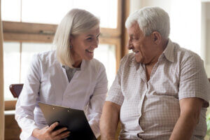 Smiling therapist empowers senior man to take charge of his health with patient education.