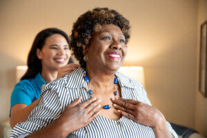 Occupational Therapist helping senior women put on necklace.