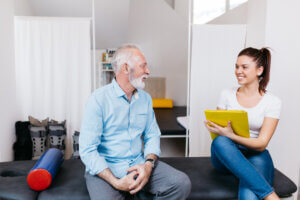 Senior man discussing his treatments with a physical therapist: Discover exciting therapist careers in care coordination.