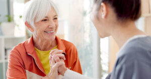 Senior woman celebrating progress with therapy team through a high-five, showcasing teamwork and healthcare support under the GUIDE Model.