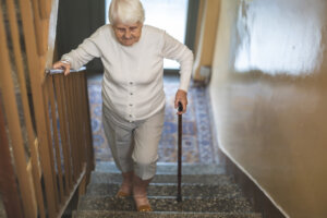 Senior woman practicing fall prevention while walking up the stairs in her house.
