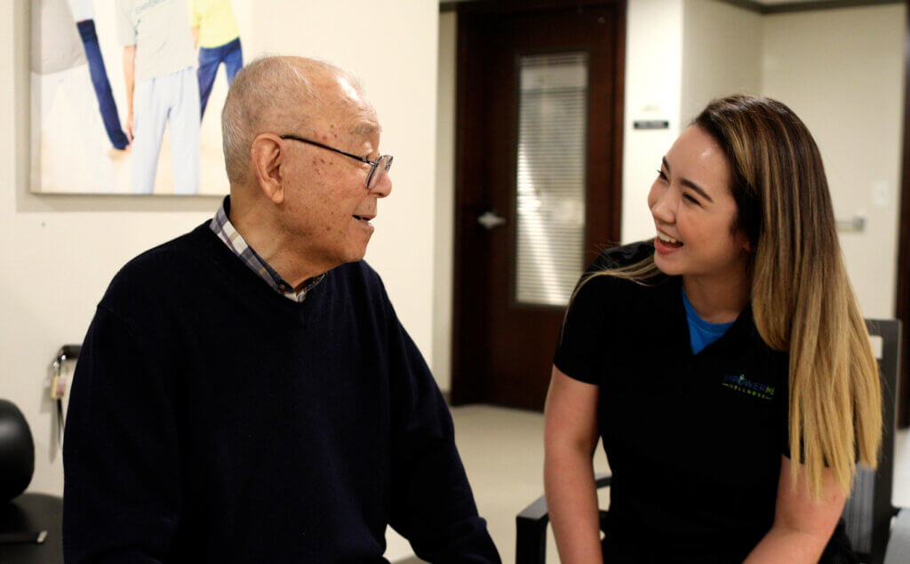 Therapist and senior resident smiling during an integrated therapy session in a senior living community.