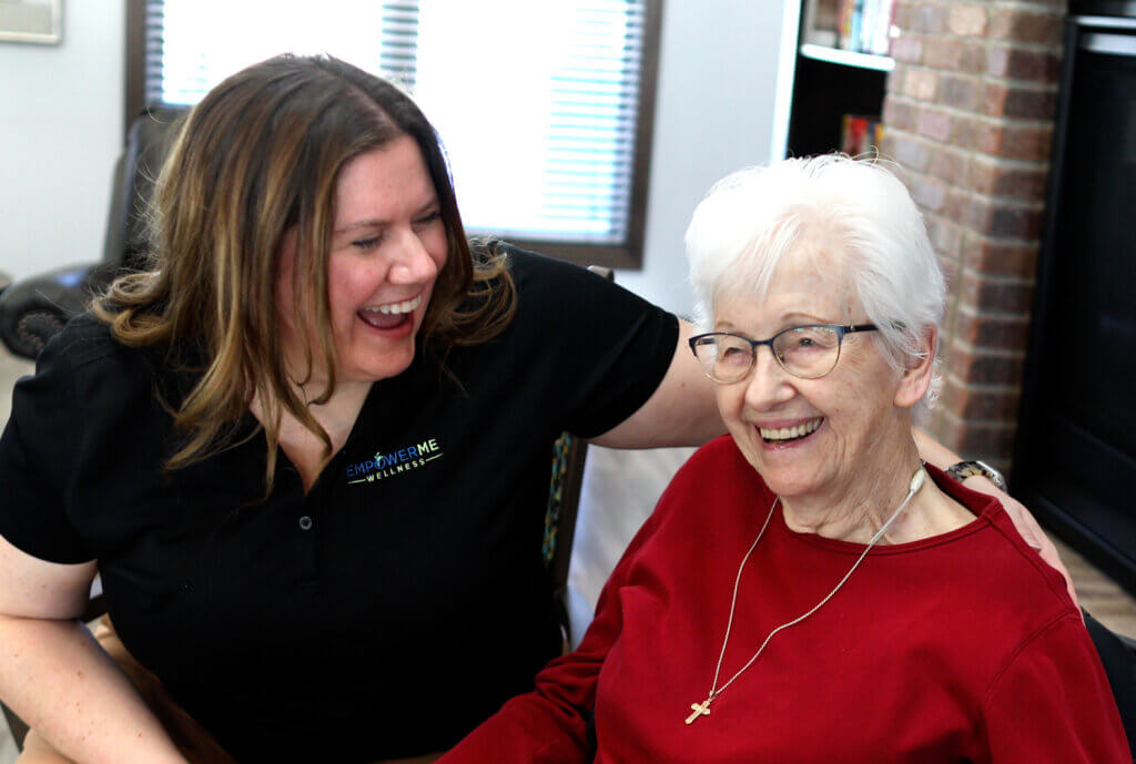 Therapist and senior resident smiling together during a therapy session supporting dementia care coordination in a senior living community.